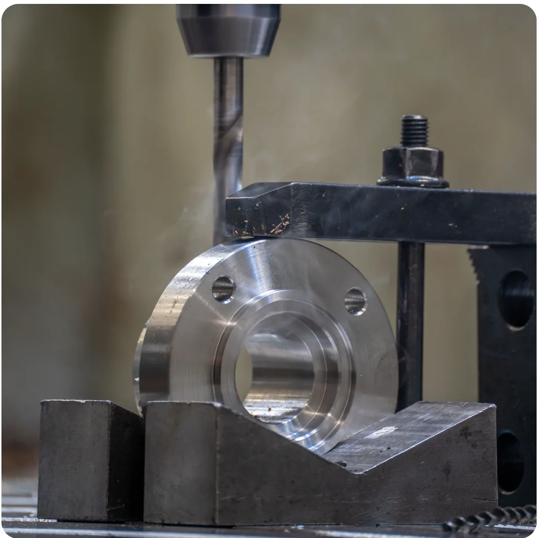 CNC drill machining a steel flange clamped in a V-block