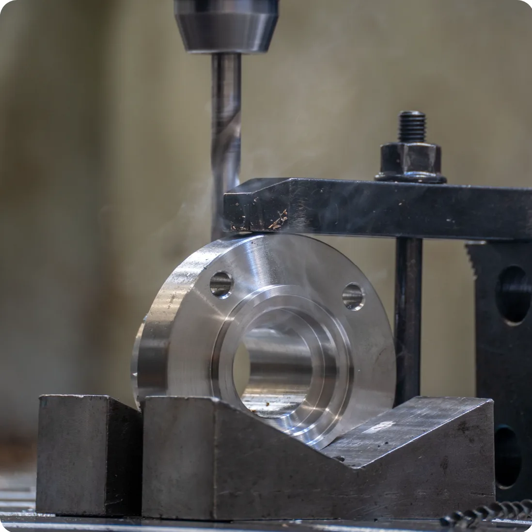 CNC drill machining a steel flange clamped in a V-block