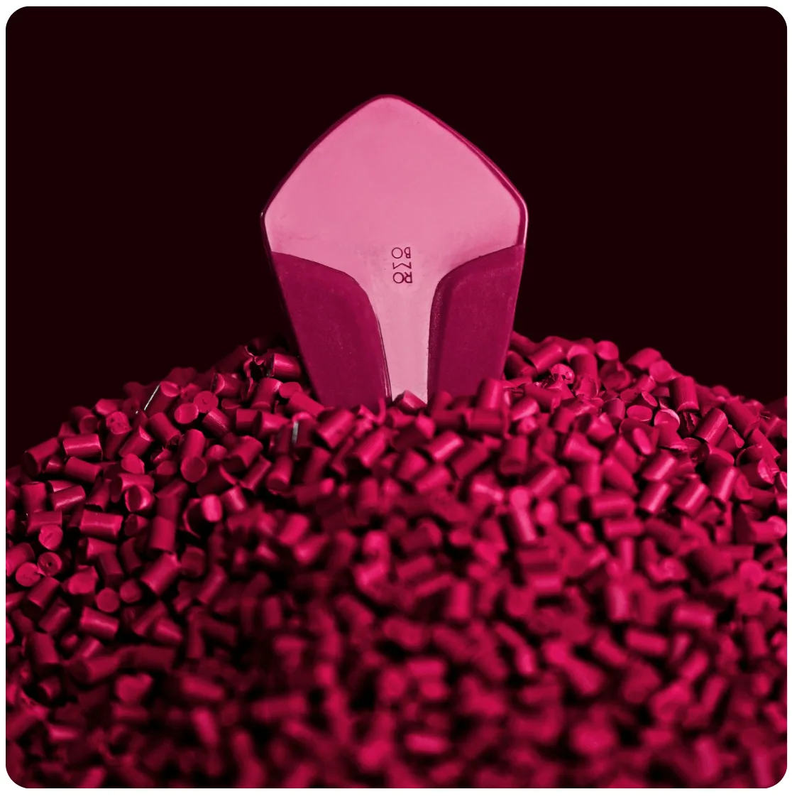 Molded part standing in a bed of magenta polymer pellets