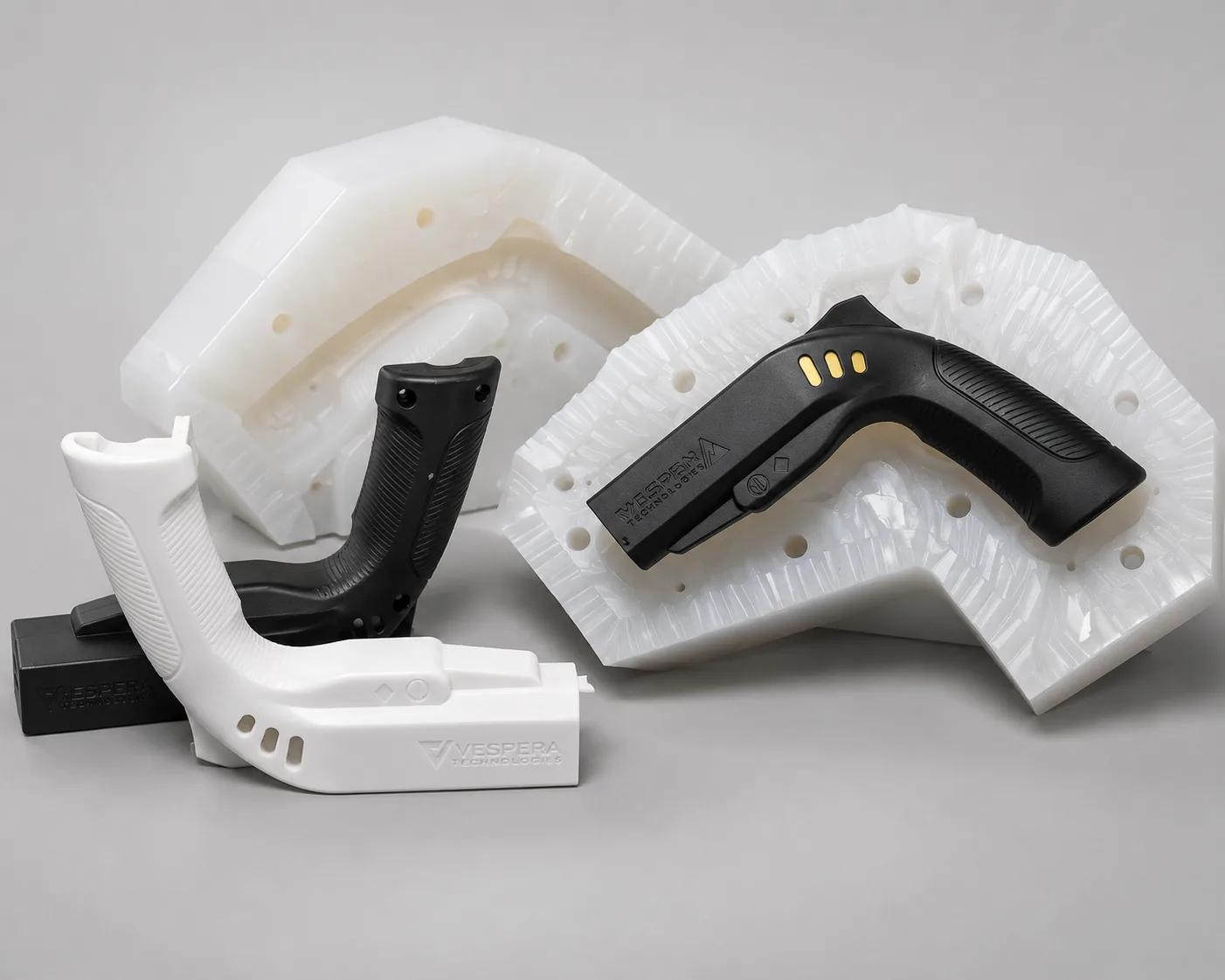 White and black 3D printed master pattern grips beside their silicone molds