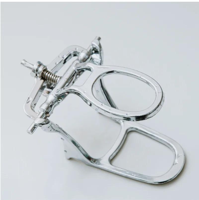 Chrome-plated dental articulator on a neutral studio background