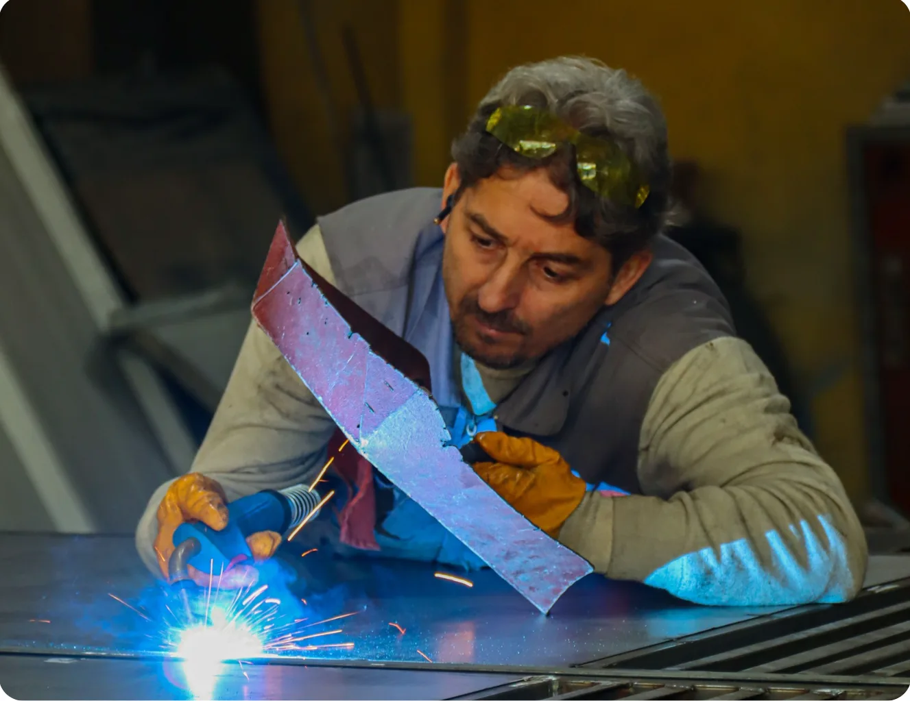 Welder inspecting a fabricated sheet metal part over sparks
